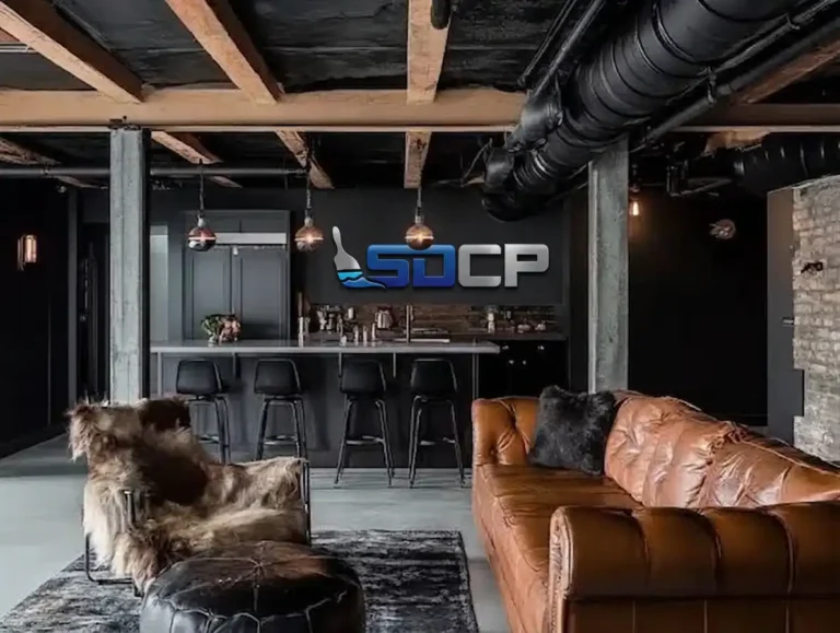 Industrial-style basement with black ceiling paint, exposed ductwork, beams, and pipes, showing how a black painted ceiling helps conceal ceiling elements while creating a modern, sophisticated look.