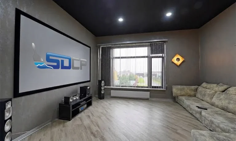 Modern living room with black ceiling paint, gray walls, large window, and home theater setup showing how a black painted ceiling creates a bold statement design feature.