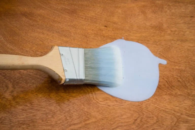 Applying Minwax Polycrylic water-based wood finish with a synthetic bristle brush on a hardwood surface indoors