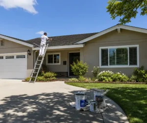 Two painters on ladders repaint a stucco ranch house exterior, showing how much does it cost to paint a ranch house on a sunny day