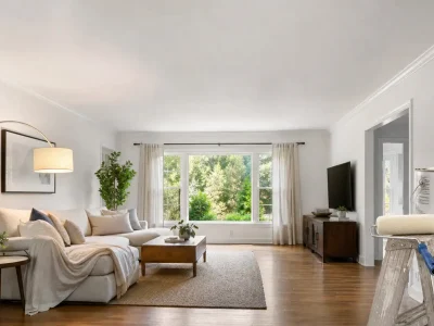 Bright living room with a smooth white ceiling, showing what sheen for ceiling paint works best, with a paint roller and can on a ladder